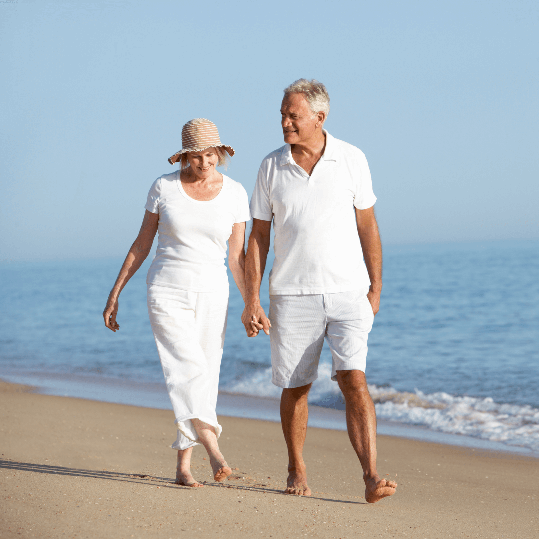 Un couple tout habillé en blanc se baladant sur une plage