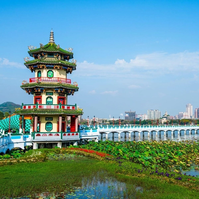 A pagoda stands on the water, with a bridge leading to its entrance, creating a peaceful, harmonious scene.