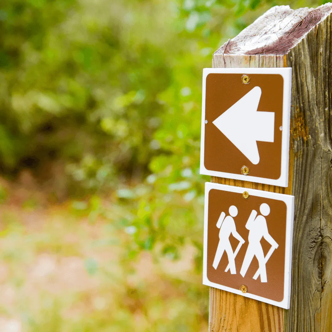 Panneau en bois avec deux flèches indiquant des directions opposées, symbolisant le choix et l'orientation.