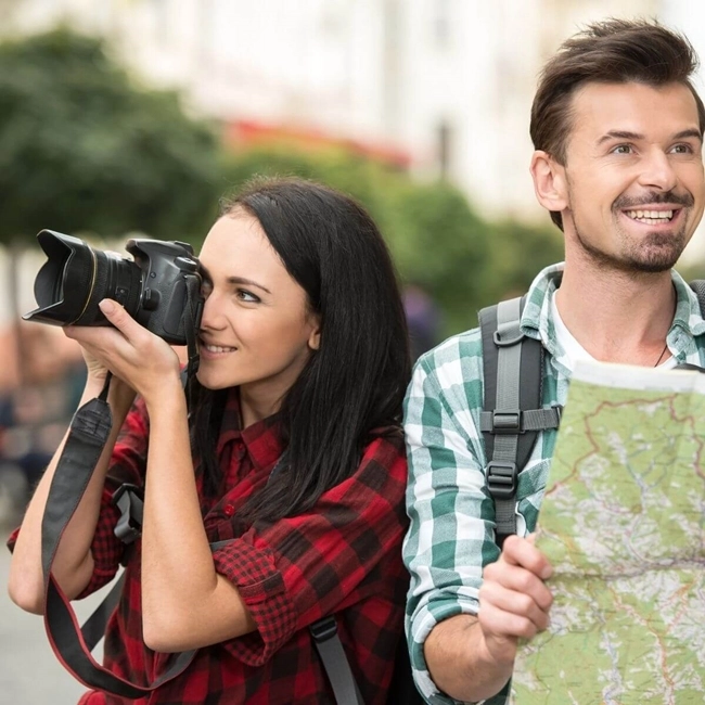 A smiling couple taking photos with a map and camera, exploring a new destination together.