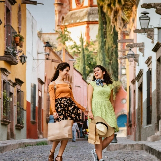  Deux femmes marchent sur une rue pavée, portant des sacs de shopping, profitant d'une journée de détente.