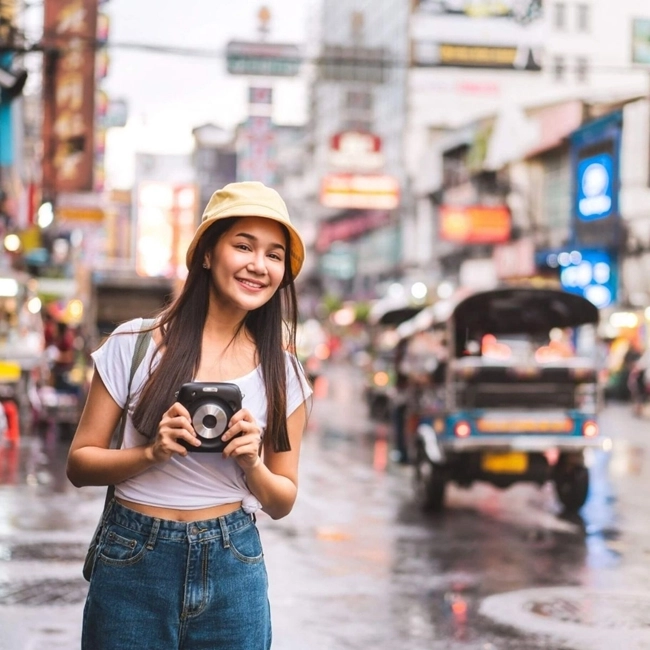 Asian woman taking a photo in a bustling city, capturing the urban essence and beauty of her surroundings.