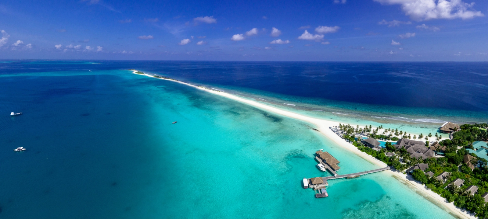 Vue aérienne d'une île tropicale, entourée d'eaux turquoise et de plages de sable blanc, offrant un paysage paradisiaque.