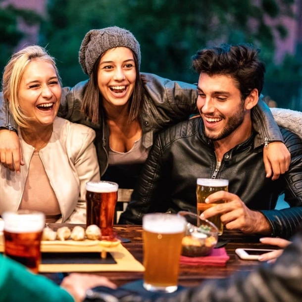 Un groupe d'amis partageant un moment convivial autour d'une bière dans un bar animé.