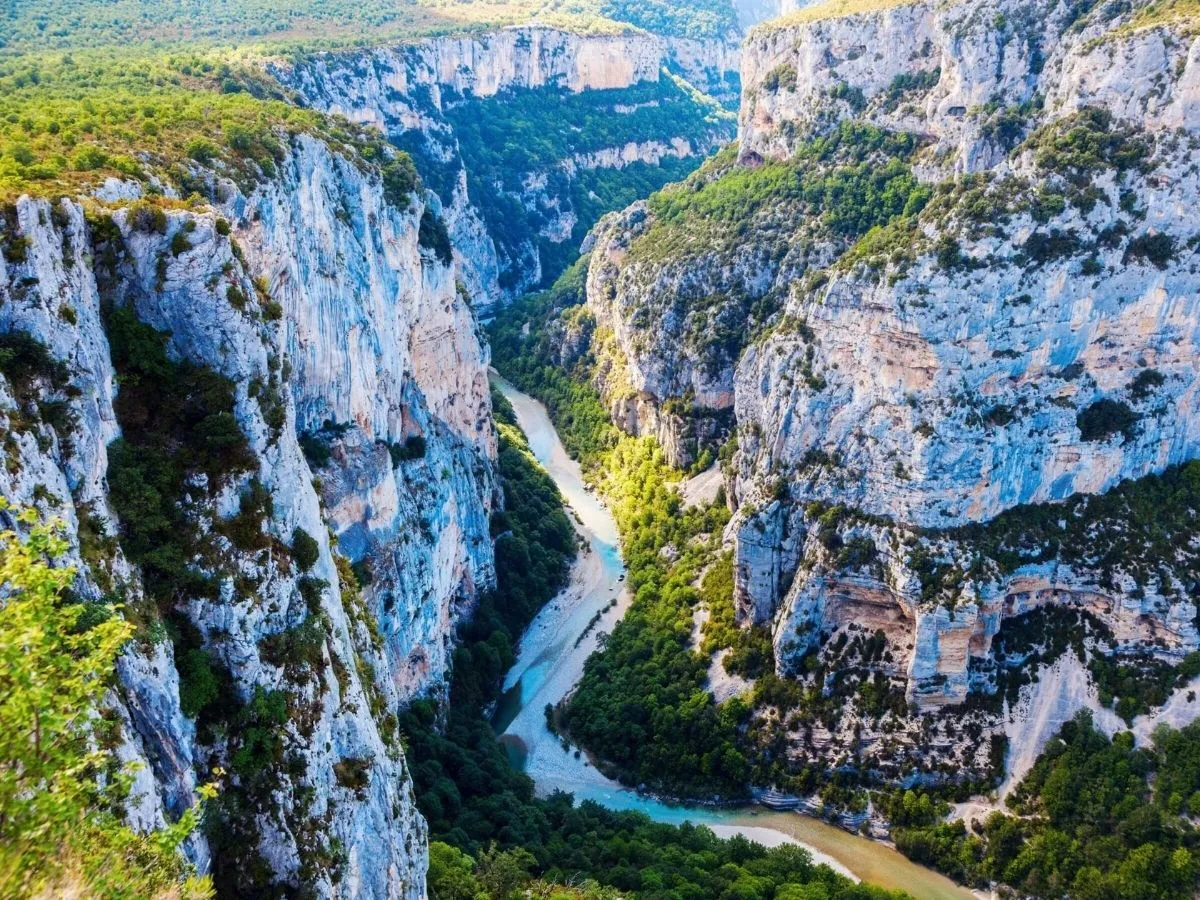 A panoramic view of the river gorge in the French Alps, surrounded by majestic mountains and lush greenery.