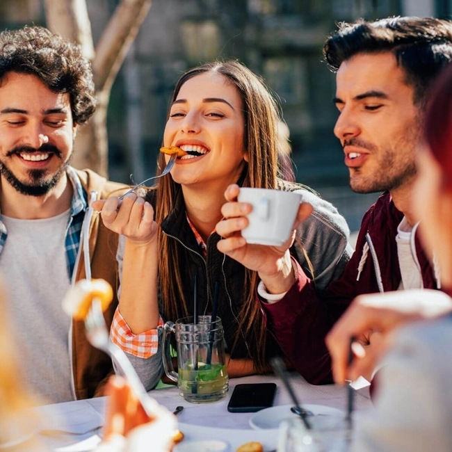 A group of friends share a meal while sipping coffee in a warm and friendly atmosphere.