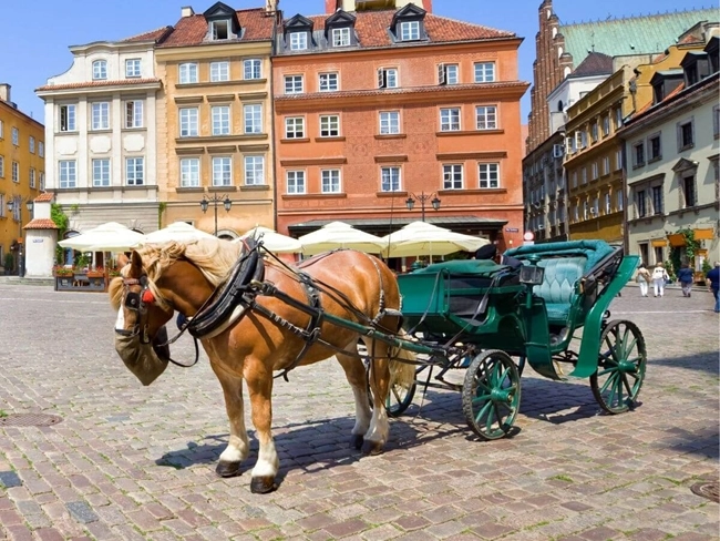 A horse-drawn carriage in the old town of Warsaw, Poland, surrounded by historic buildings.