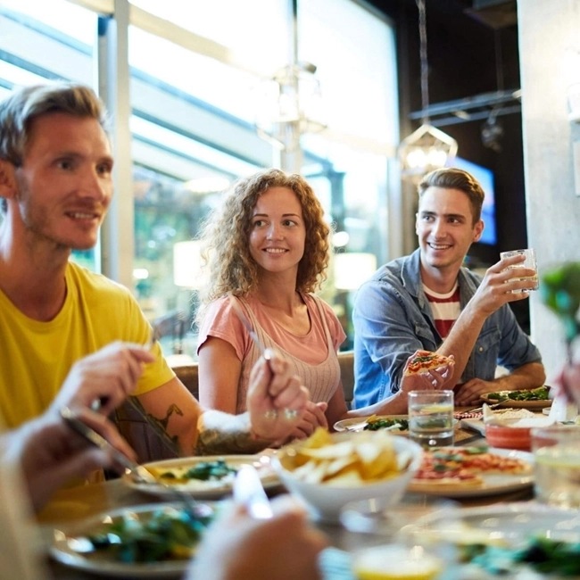 A group of people sitting at a table, sharing a convivial meal and exchanging smiles.