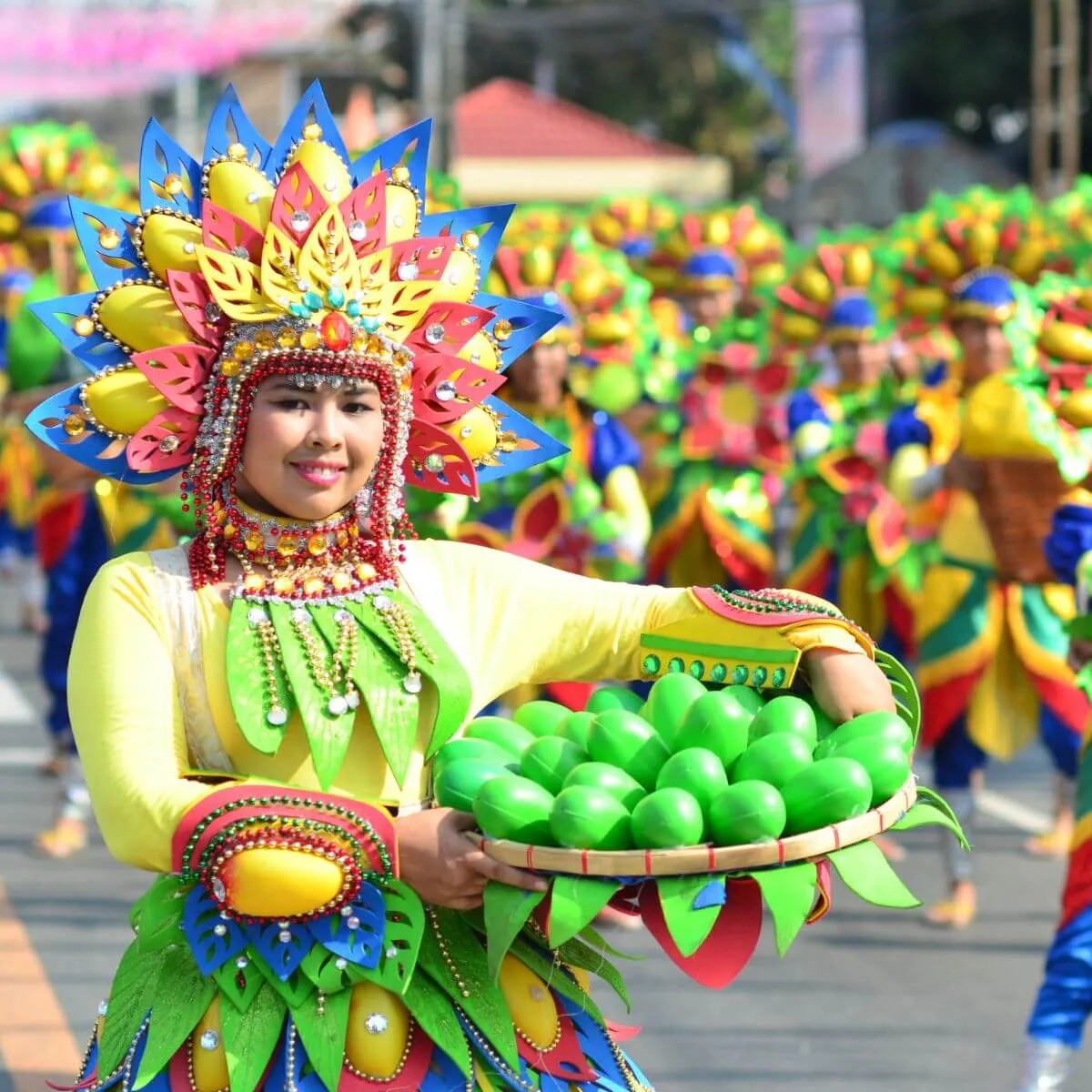 A woman in colorful costume holds a green fruit, illustrating the richness of local culture and traditions.