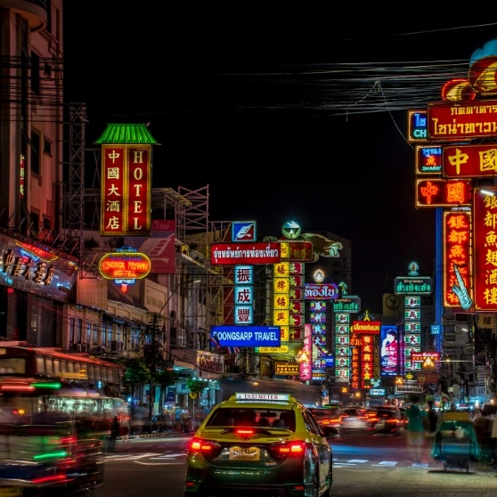 A tuk-tuk cab circulates on the street, offering a unique and colorful means of transport in a lively urban environment.