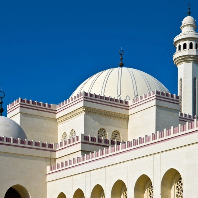 Coupole blanche et rouge d'une mosquée, symbole de l'architecture islamique, se détachant sur un ciel bleu.