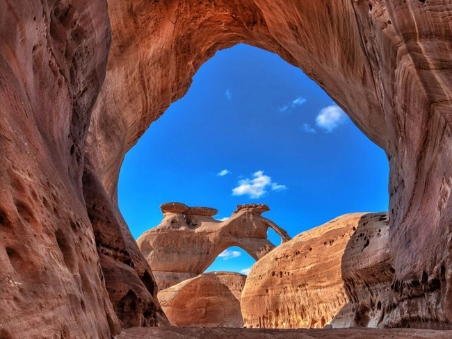 Une arche en pierre se dresse majestueusement au cœur du canyon, formant un paysage naturel impressionnant.