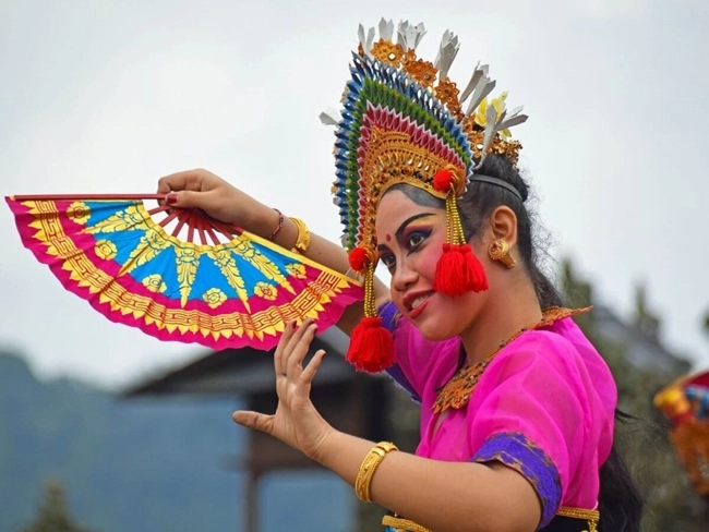 A woman in traditional costume holds a fan, illustrating the culture and elegance of her heritage.