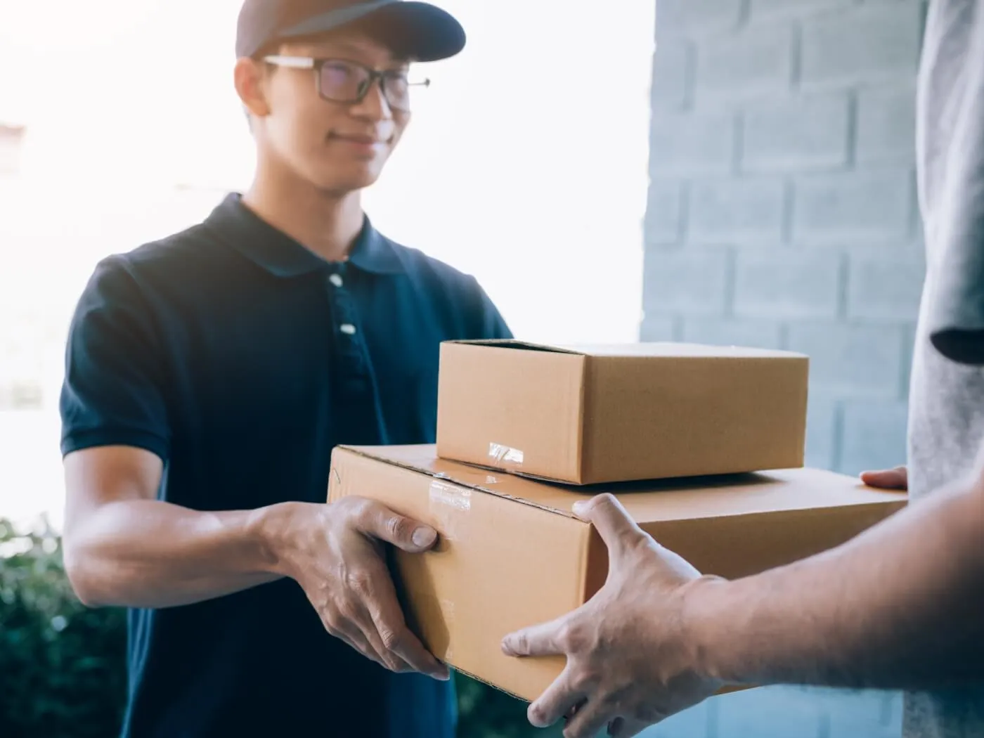 A man is handing a package to another man in a friendly exchange, showcasing a moment of delivery and interaction.