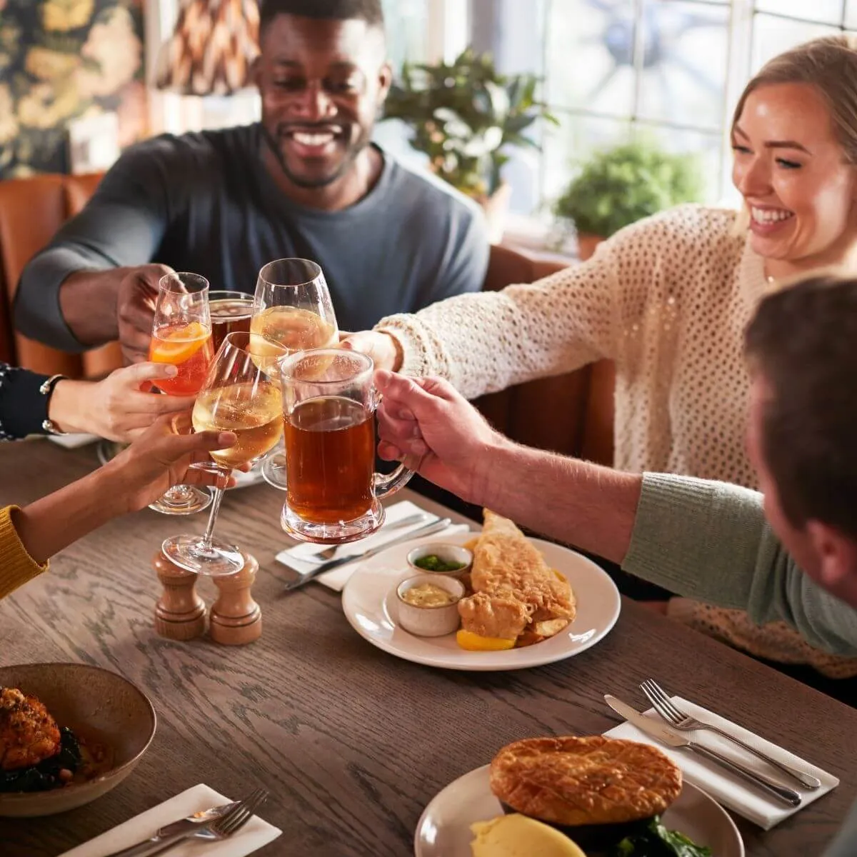 A group of people raise a glass of beer in a restaurant, celebrating a convivial moment together.