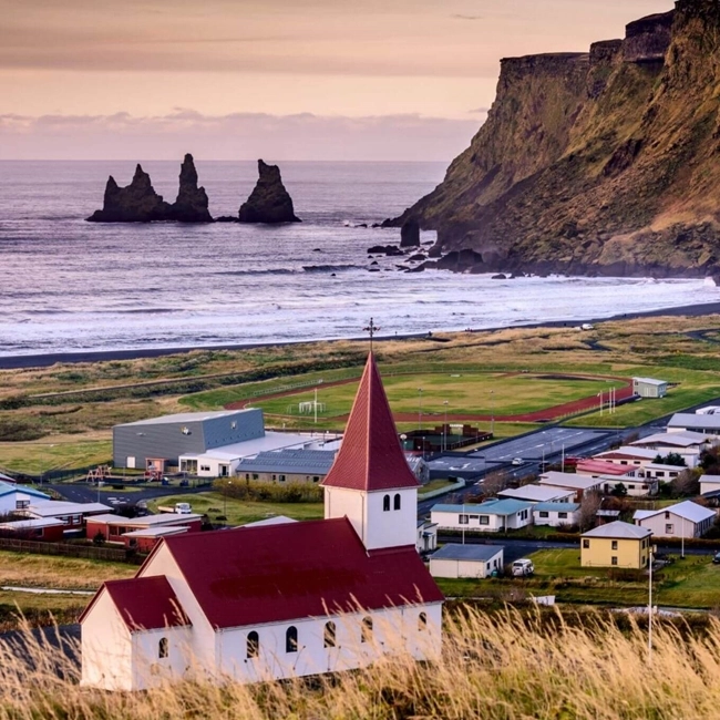 A church perched on a hill overlooking the ocean, offering a panoramic view of the sparkling waters.