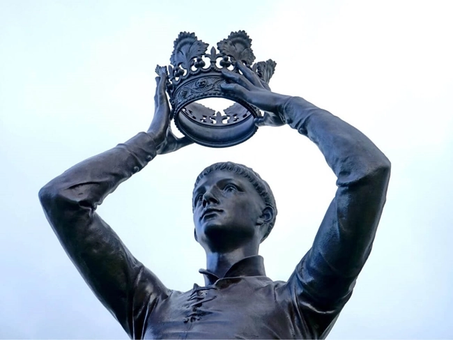 Statue of a man wearing a crown on his head, symbolizing power and royalty.