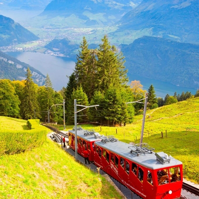 A red train traveling along a mountain slope, surrounded by majestic natural scenery.