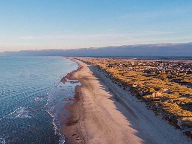 Aerial view of a beach with sand dunes, highlighting the natural beauty of the coastline.