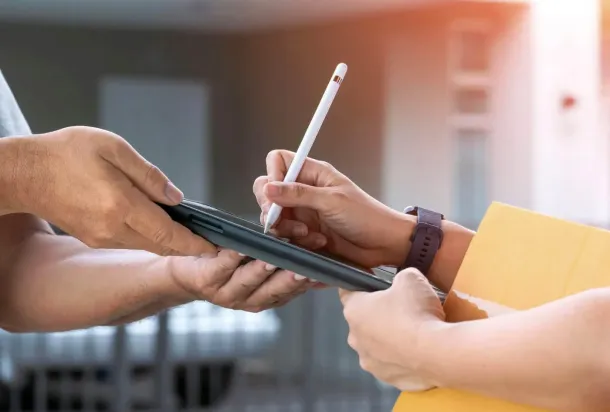 A man hands over a parcel to another person in a friendly, professional exchange.