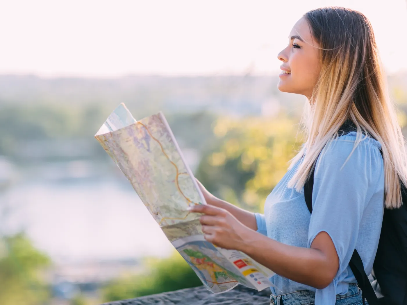 A young woman smiles while examining a map, showcasing her enthusiasm for exploration and adventure.