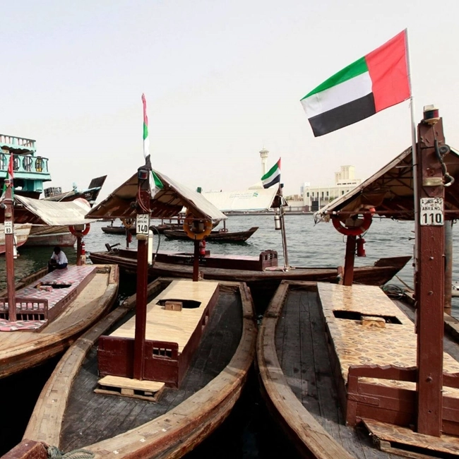 Boats moored in Dubai's marina, reflecting modern architecture and the surrounding urban landscape.