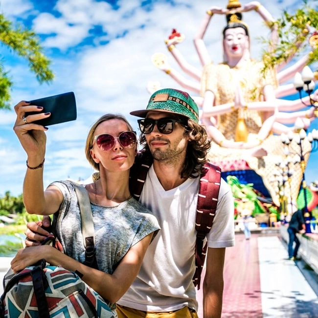 Un couple prend un selfie devant une statue, capturant un moment joyeux et mémorable ensemble.