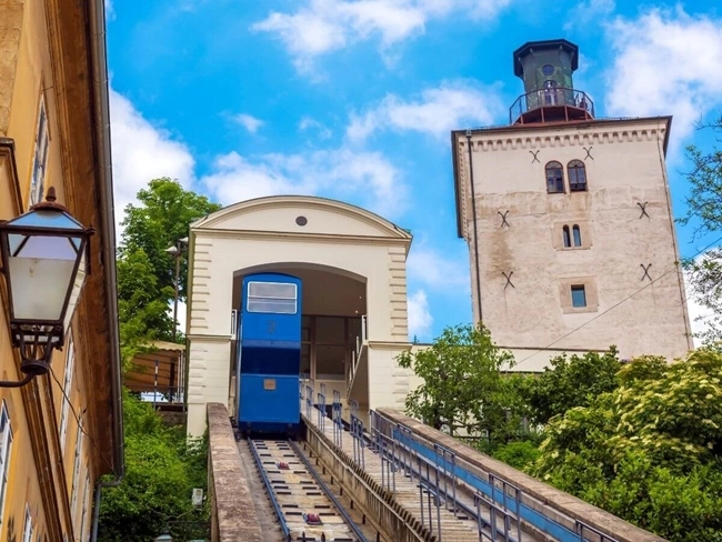 Blue elevator rising to a building topped by a clock, symbolizing movement and time.