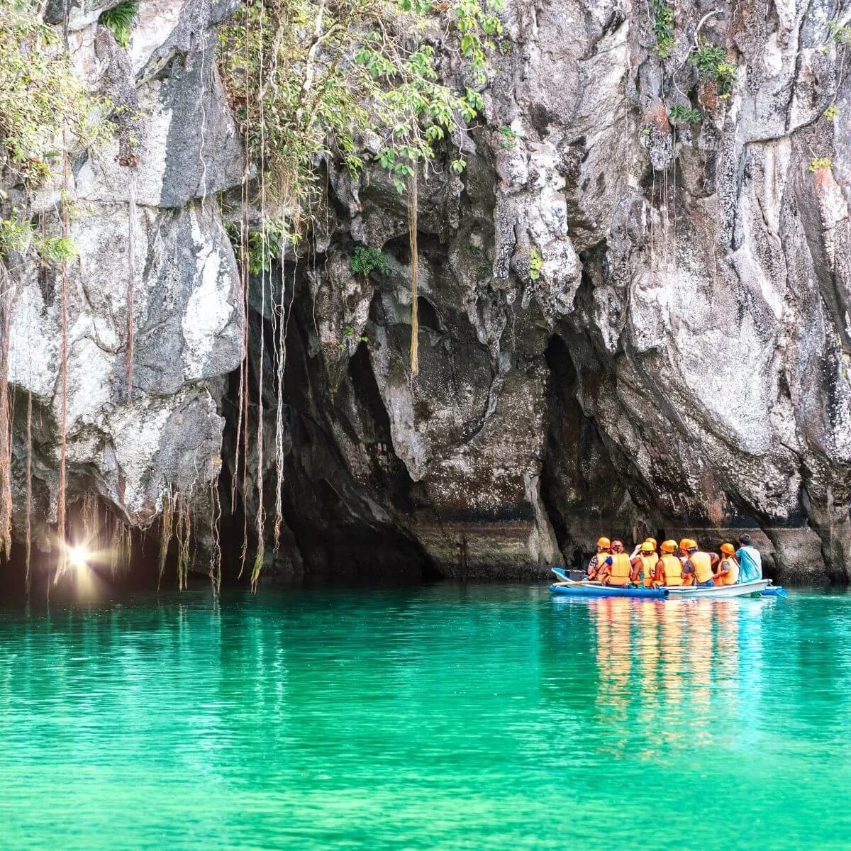 A group of people in a boat in front of a cave, exploring a fascinating natural landscape.