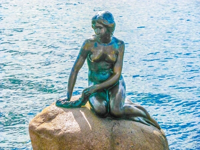 Statue of the Little Mermaid in Copenhagen, emblematic and delicate, overlooking the harbor with grace and beauty.