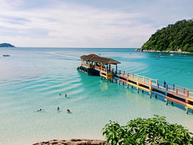 A quay overlooking a beach, with a boat moored in the calm water, creating a peaceful, picturesque scene.