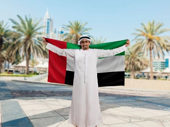 A man holding the UAE flag in a modern city, symbolizing national pride.