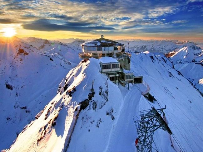 Mountain summit with chairlift and building, offering panoramic views of the surrounding ski slopes.