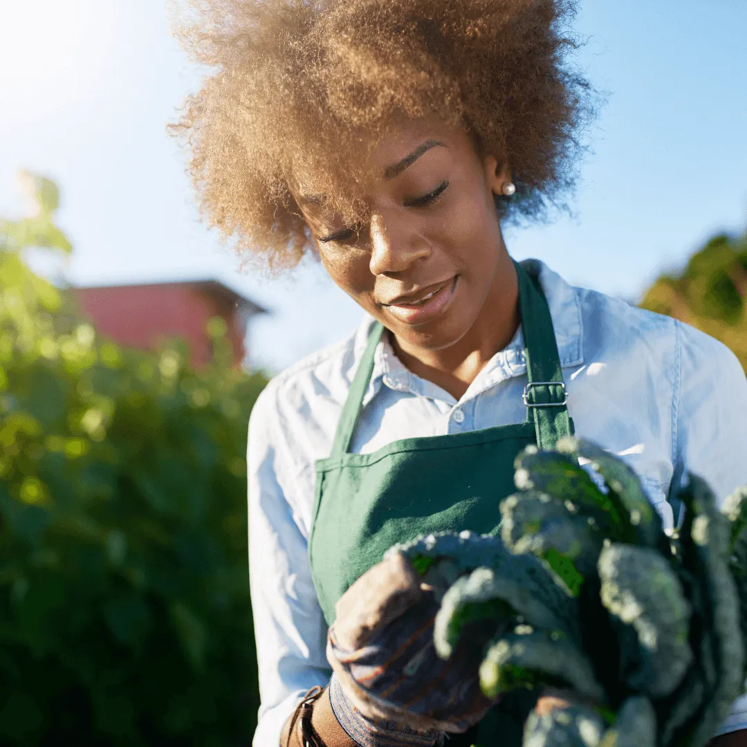  Une femme en tablier tient un légume vert, illustrant la préparation culinaire et l'importance des aliments frais.