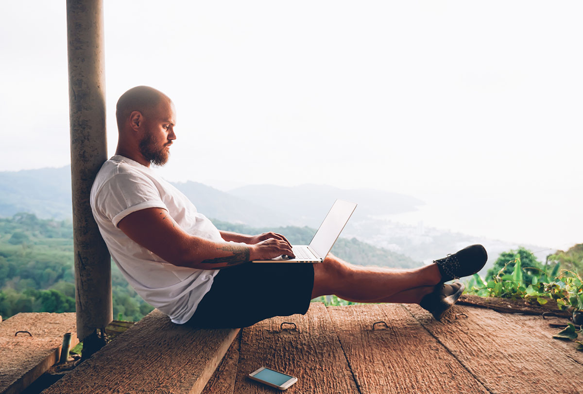 A man is relaxing and browsing the internet in front of a scenic view