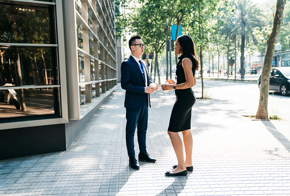 Male and female office workers talking in a modern city street.